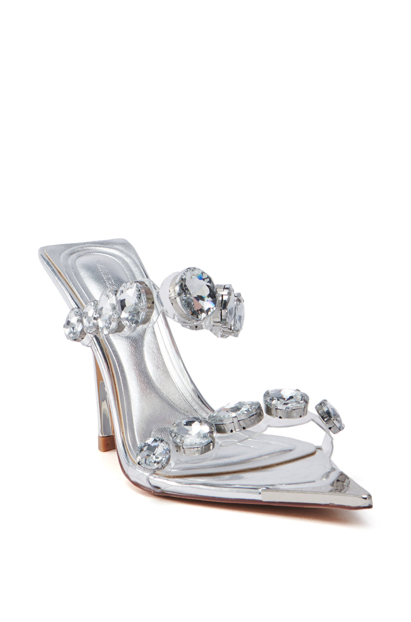 The AZALEA WANG PAOLINA Silver Rhinestone Chunky Heel Sandal features a pointed toe, stiletto heel, and sparkling gemstone straps. Its lightly tinted beige sole contrasts with the transparent design. Crafted from metallic faux leather, it offers a sleek, modern look.