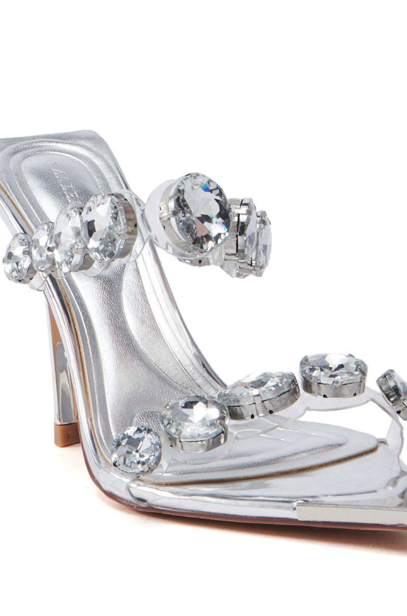 The AZALEA WANG PAOLINA SILVER RHINESTONE CHUNKY HEEL SANDAL features a clear high heel with large silver rhinestones, sparkling strap details, a modern transparent vamp, and a square toe.