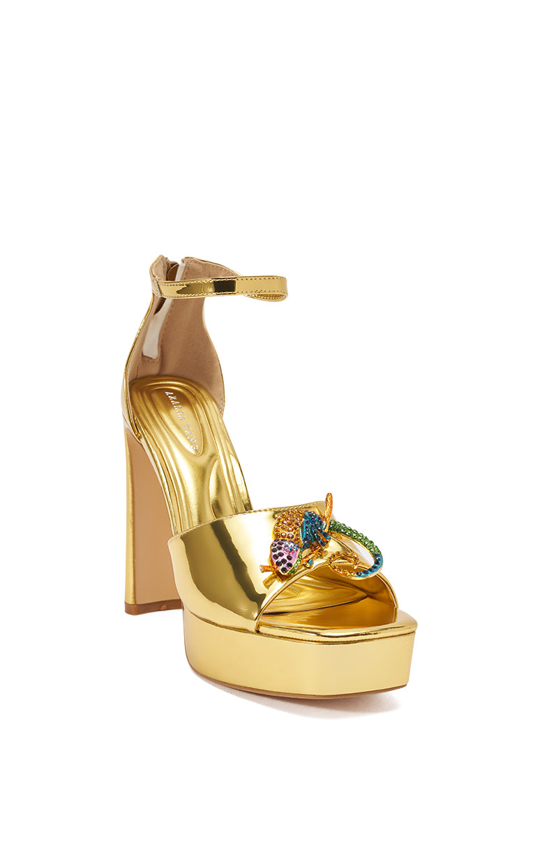 Make a bold statement with the AZALEA WANG PASQUALE GOLD IGUANA EMBELLISHED SANDAL—a metallic gold high-heeled platform with an ankle strap and multicolored jeweled serpent detail across the front. 8