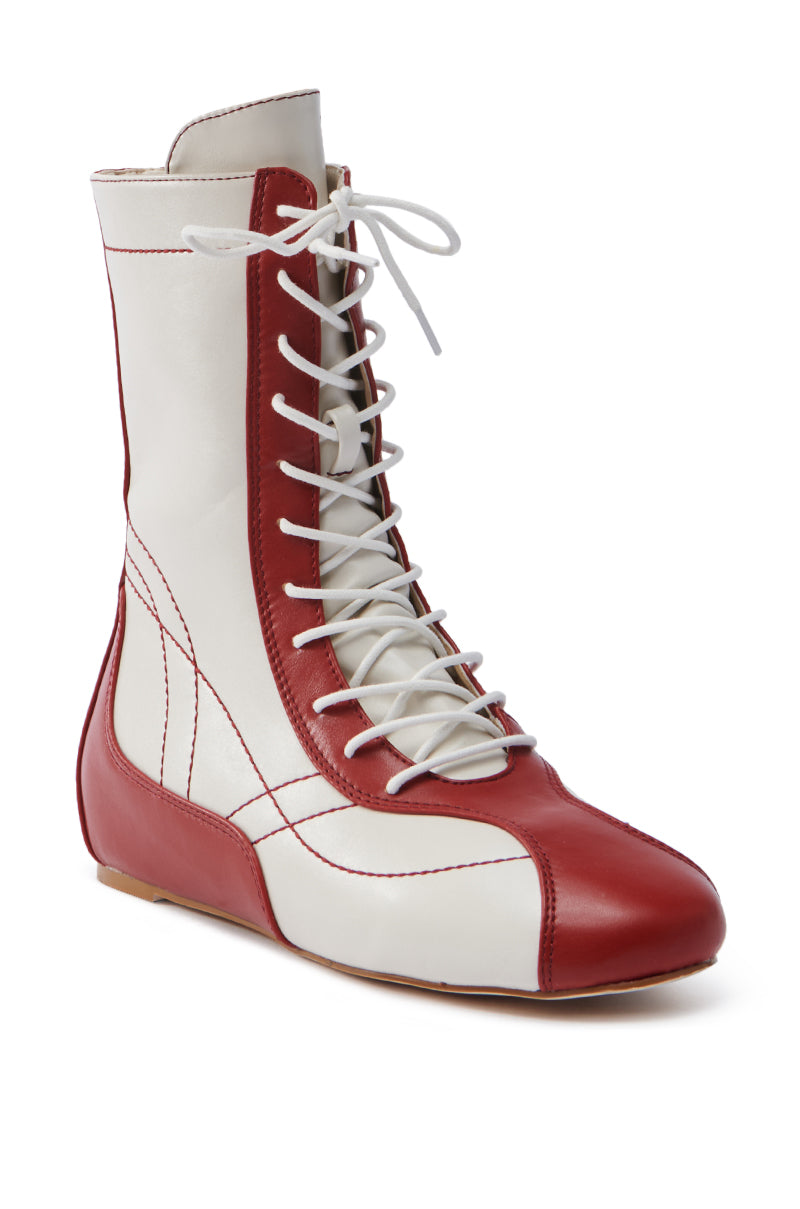 The AZALEA WANG PASSER SPORTY FLAT BOOTIE is a faux leather high-top featuring a red and white color scheme with intricate stitching, white laces reaching up to the ankle, and a lace-up vamp for a balanced sporty yet stylish look.