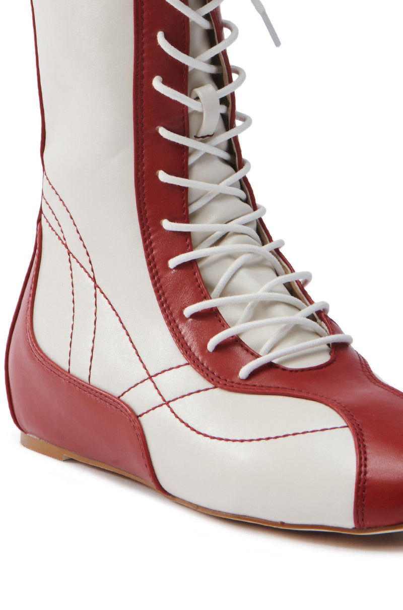 Close-up of the AZALEA WANG PASSER SPORTY FLAT BOOTIE. This faux leather bootie features a red trim, brown sole, and stylish lace-up vamp. Intricate stitching adds a unique pattern to its charm.