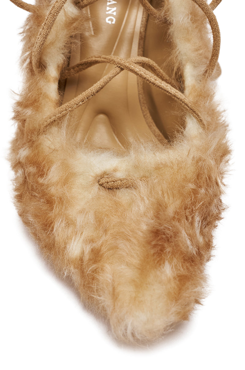 A close-up of the AZALEA WANG PAULHINO SNOW LEOPARD STRAPPY PUMP, a pointed-toe shoe with light brown faux fur, crisscross suede laces, and a chic stiletto heel.