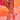 A person in a pink satin lace dress poses with crossed legs, highlighting the AZALEA WANG PAVARTI PINK BALLET PUMP with a satin upper and ribbon ankle straps against a warm orange-pink background.