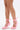 A person stands on a white background wearing the AZALEA WANG PAVARTI PINK BALLET PUMP—light pink satin heels with ankle ribbons, bow details, open square toes, and medium-height block heels inspired by ballet style.