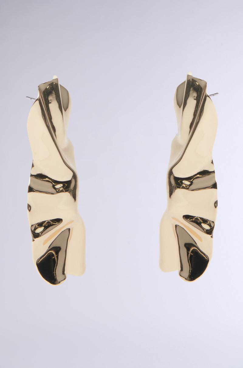 The ITS ORGANIC EARRING features faux gold abstract sculptural earrings with twisted, organic shapes, set against a neutral gray background. Their shiny surface beautifully reflects light, highlighting the wavy design. 2