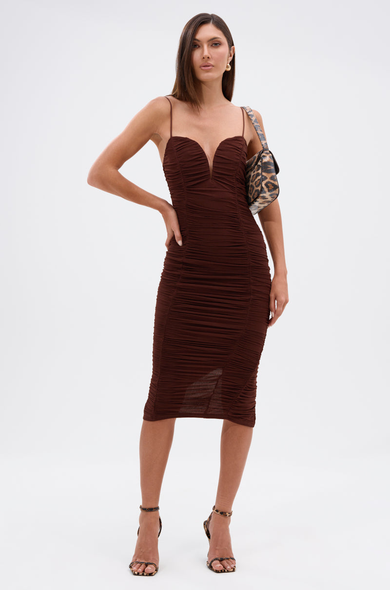 A woman models the DINA MESH MIDI DRESS, showcasing its figure-flattering fit with thin spaghetti straps and a sweetheart neckline. She pairs it with strappy heels and a chic small patterned shoulder bag. 4