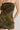 A person is wearing the DELPHI LEOPARD PRINT BURNOUT MINI DRESS, a strapless, form-fitting dress with a green and brown design. The person's left arm is bent with a hand resting on the hip, highlighting the dress's pattern and fit against a plain, light-colored background.