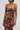 Wearing the HEAVEN SENT MESH MIDI DRESS, a woman poses against a neutral backdrop. The dress, adorned with abstract patterns and earthy tones, features thin straps and a ruched design that enhances her figure as she turns her head slightly to the side.