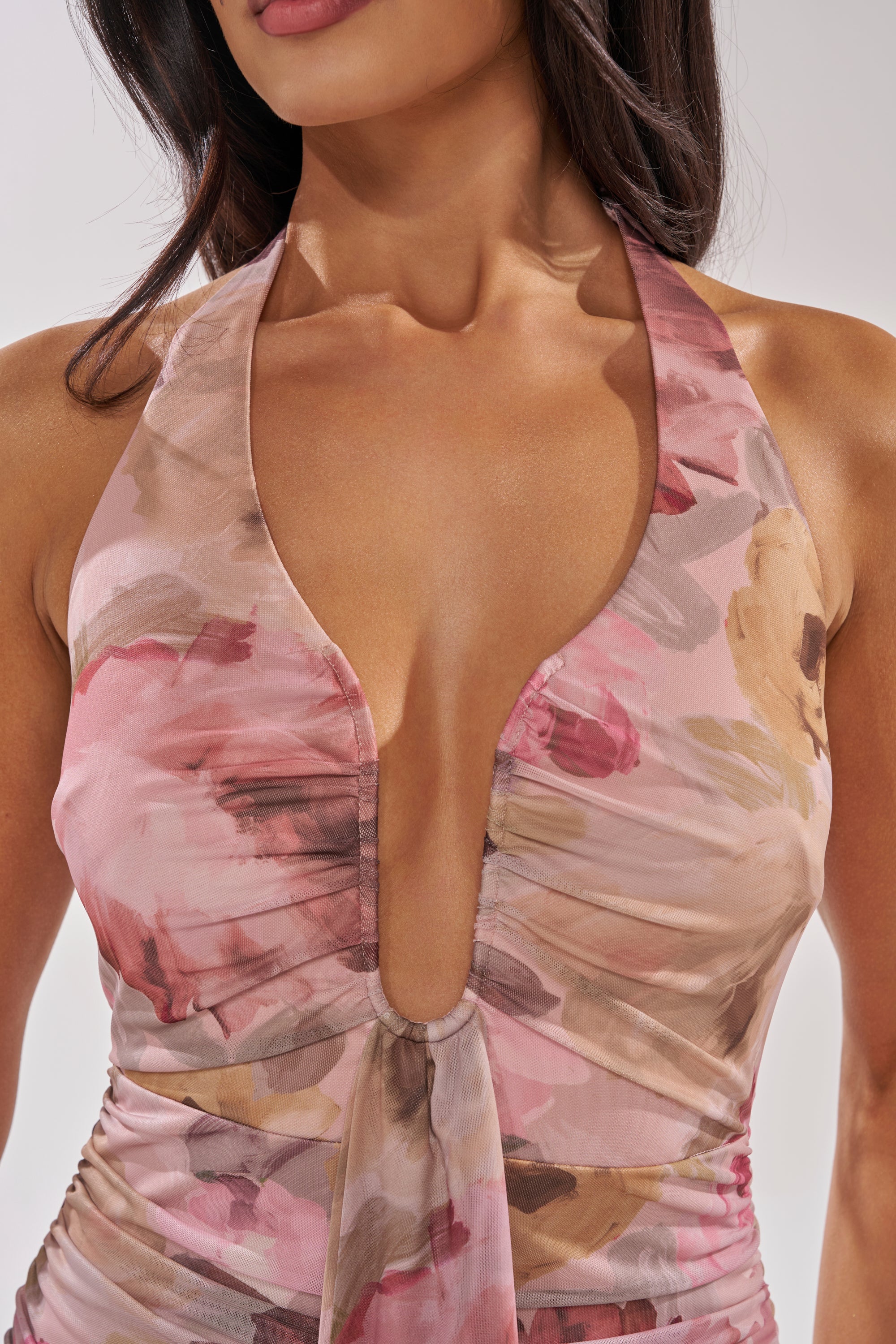 A woman wears the I DON'T CHASE FLORAL MAXI DRESS, a sleeveless, deep V-neck dress featuring a watercolor floral pattern in pink, mauve, and beige. The image is cropped to display her upper body and part of her face. 4