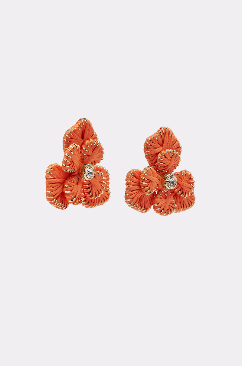 The ON THE BEACH EARRINGS are orange floral statement earrings featuring textured petals and a clear gemstone at the center of each flower, shown against a plain light background. 2