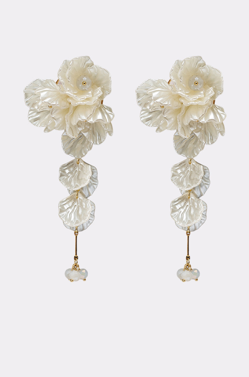 The FOR THE PARTY EARRING features bold drop earrings with white, textured floral and leaf designs, gold accents, and a small white bead at the bottom—perfect for any occasion. Shown against a plain light background. 1