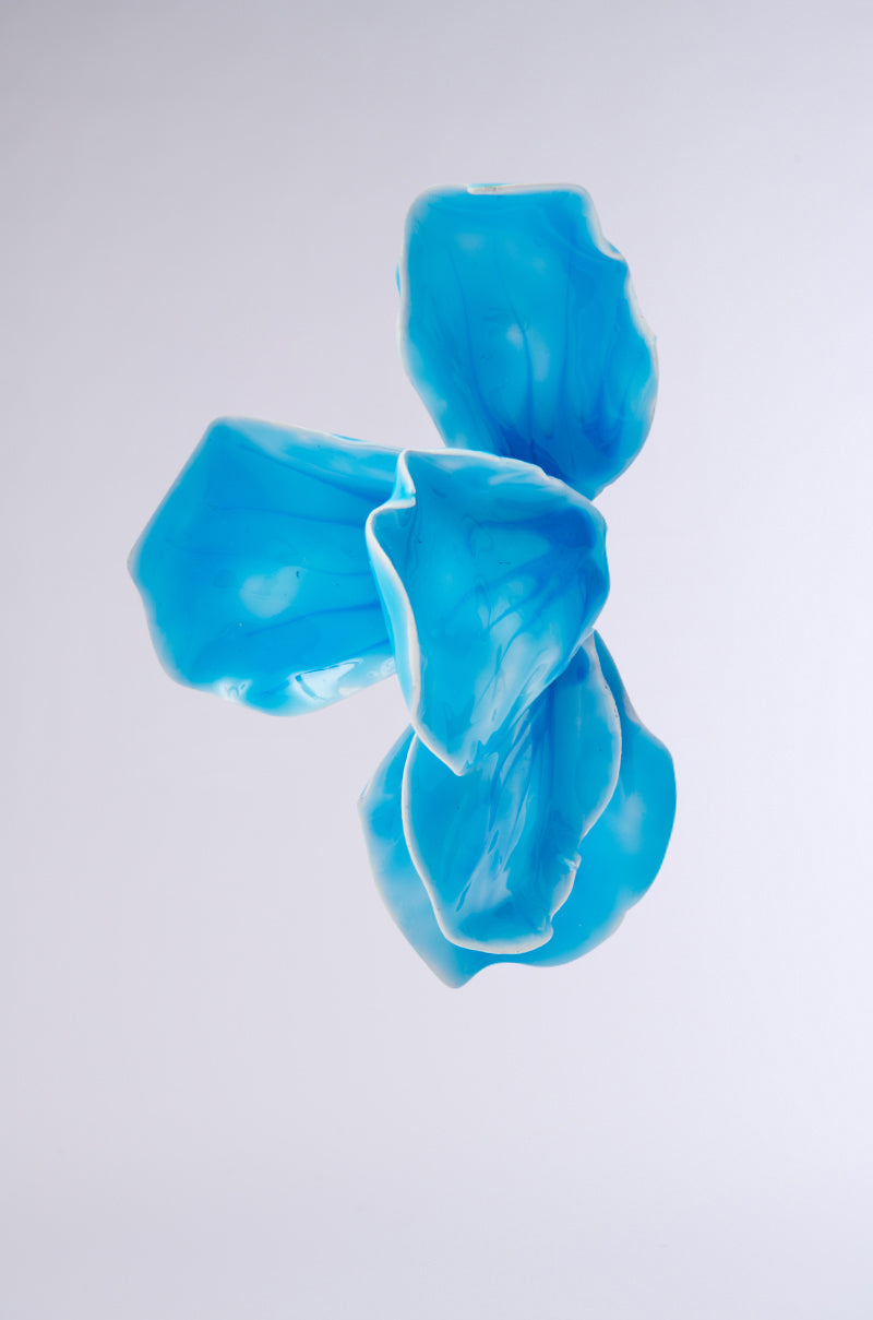 The NO BLUES EARRING features four translucent blue, petal-like shapes with white edges arranged in a loose cluster, creating an airy floral silhouette against a light gray background. 3
