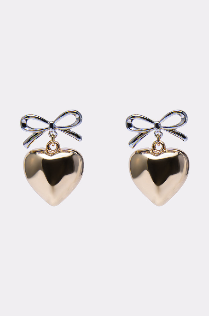 The BIG HEART EARRING features gold heart shapes with silver bow designs on top, shown against a plain white background. 0