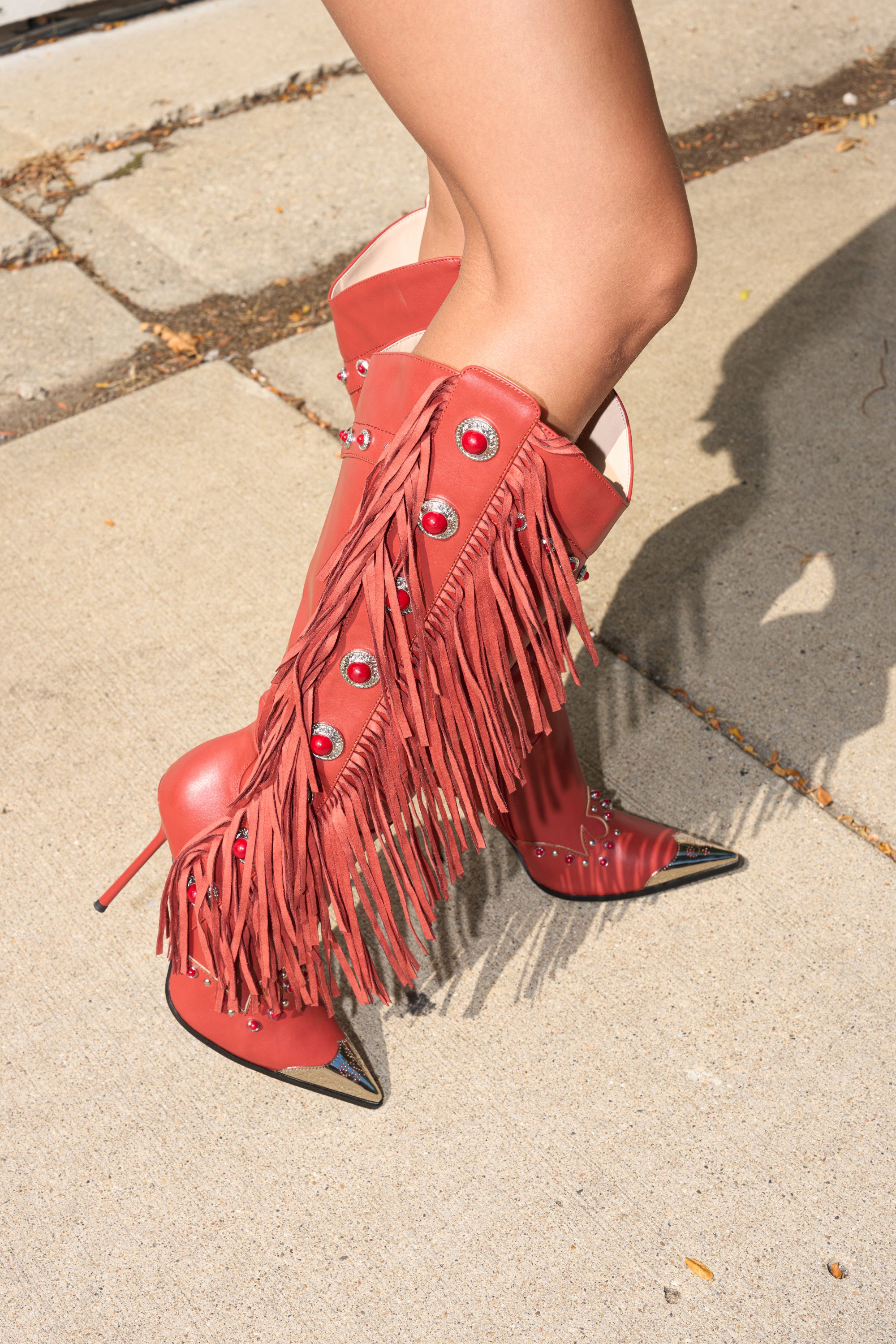A person stands confidently on a concrete sidewalk wearing the AZALEA WANG PELAGIANA RED WESTERN POINTED TOE STILETTO BOOT. 2