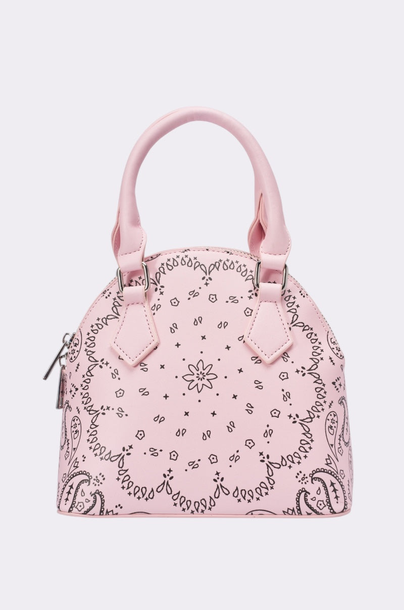 The ASTRA PAISLEY PRINT BAG is a small, dome-shaped pink faux leather handbag with short handles, a silver zipper, and a black paisley floral bandana print—an ideal Y2K purse to complement any trendy outfit.