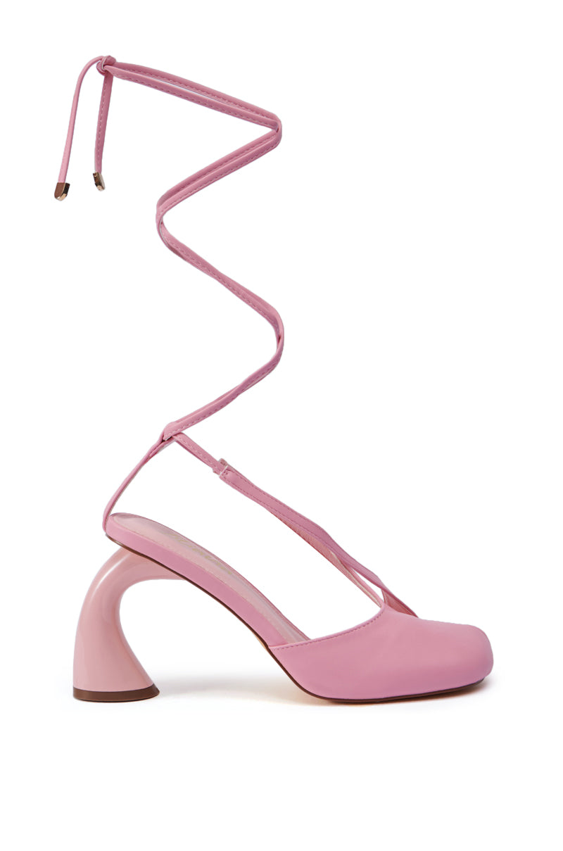 The PIRATE PINK PUMP is a standout piece with its distinctive chunky sculpted heel and long wraparound ankle straps. This stylish shoe features a smooth finish and square toe design, making it ideal for those who love the balletcore trend.