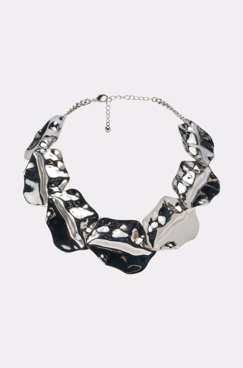 The MOLTEN NECKLACE is a chunky, sculptural silver piece with large, irregular metallic segments, one in a lighter silvery-white tone, all linked together and finished with an adjustable chain clasp.