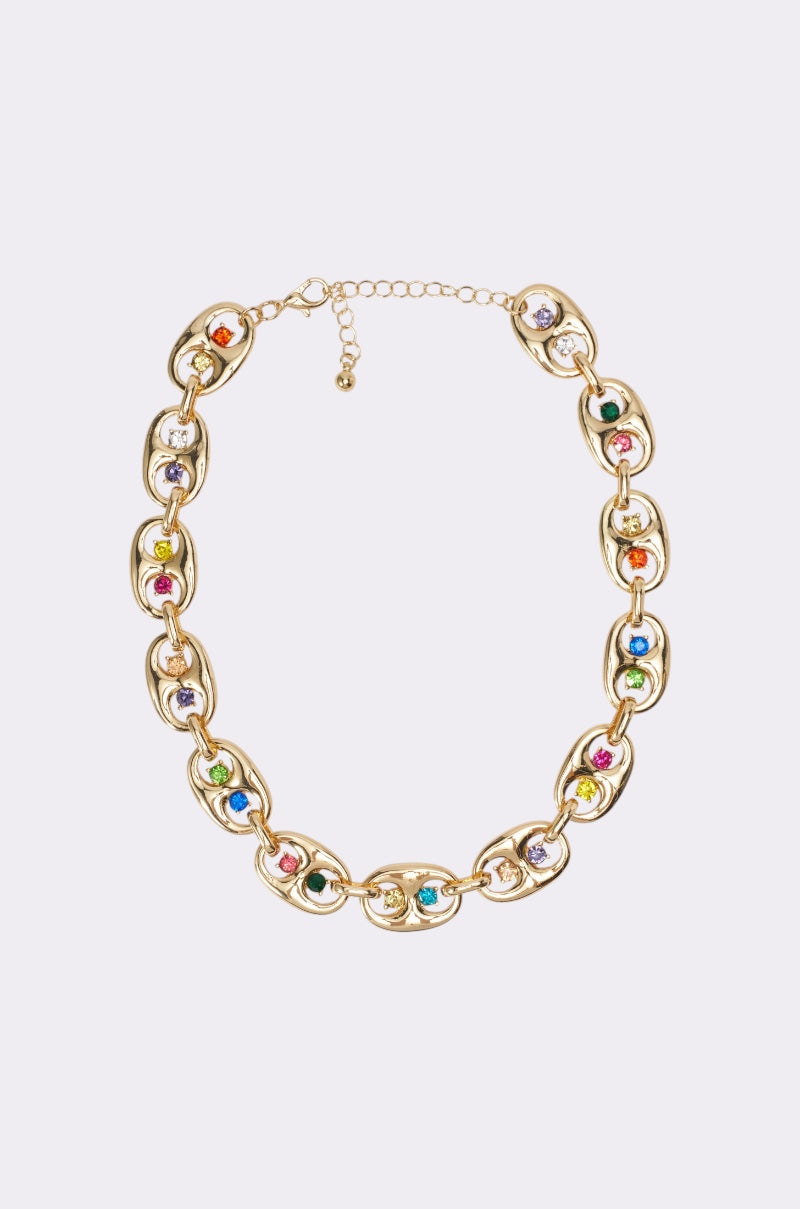 The A GOOD TIME NECKLACE features gold oval links, each adorned with a colorful gemstone for a radiant rainbow effect—a vibrant festival piece reminiscent of rhinestone gold necklaces. Shown on a light background. 1