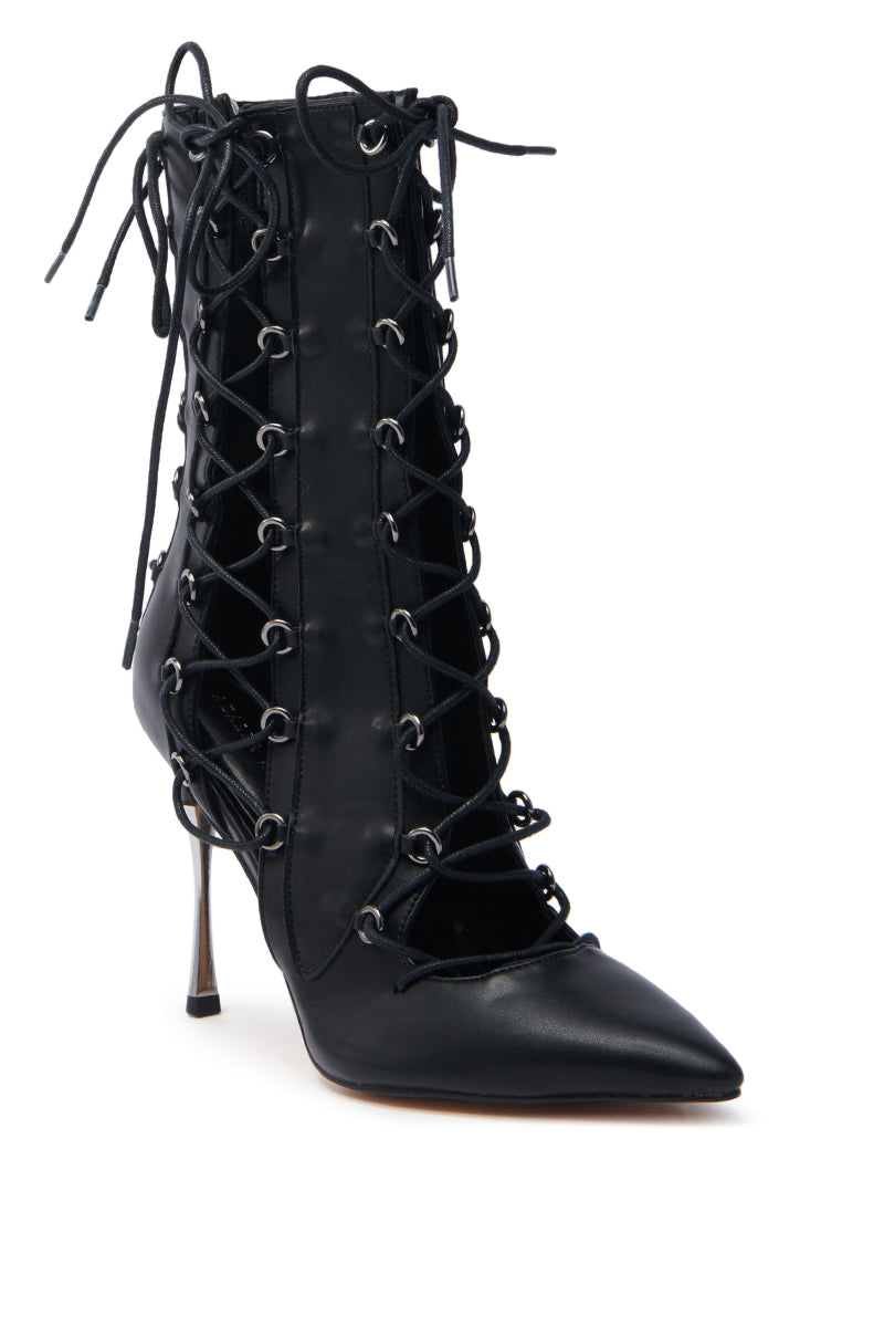 The AZALEA WANG PONCIA BLACK LACE UP BOOTIE is a black stiletto heel bootie with a pointed toe and intricate lace-up design. This faux leather bootie features numerous metal eyelets, creating a stylish and edgy look.