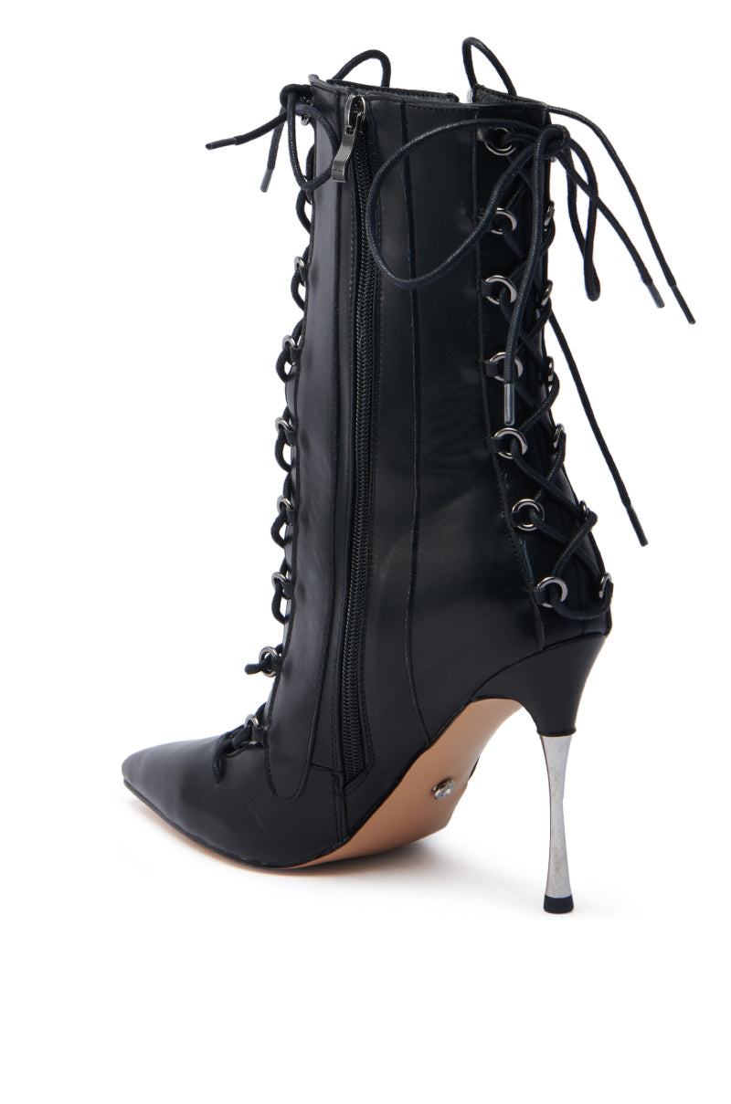 The AZALEA WANG PONCIA BLACK LACE UP BOOTIE features a black faux leather design with a silver stiletto heel, zipper closures, and detailed eyelets on the sides, offering both style and sophistication.