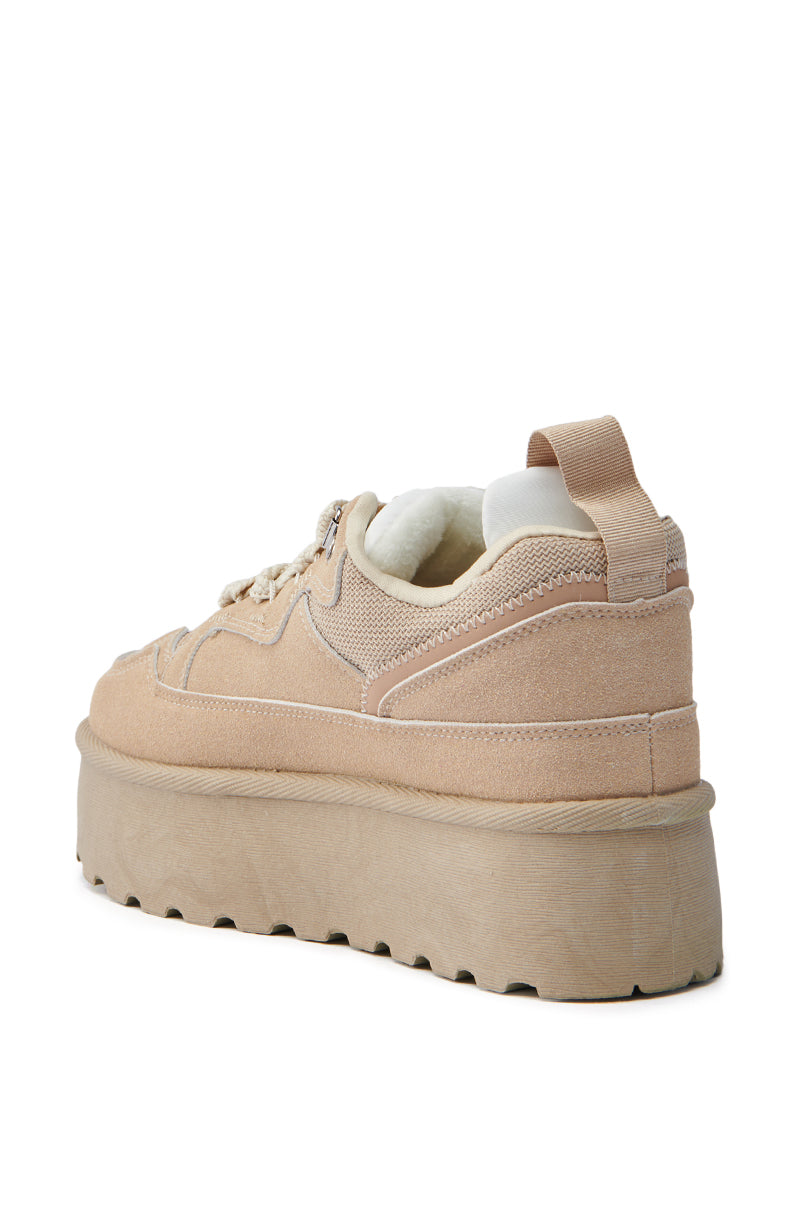 The POPULARITY SAND FLATFORM SNEAKER is a beige suede shoe with a chunky sole, lace-up design, and almond toe. It features a loop tab at the heel with a textured surface for a casual and trendy look, as seen from the back. 5