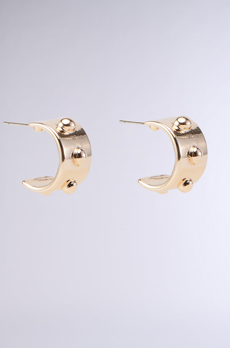 A pair of CHUNKY GOLD HOOP EARRINGS with an elegant and unique design, featuring three raised circular studs on each hoop, set against a simple gray background.