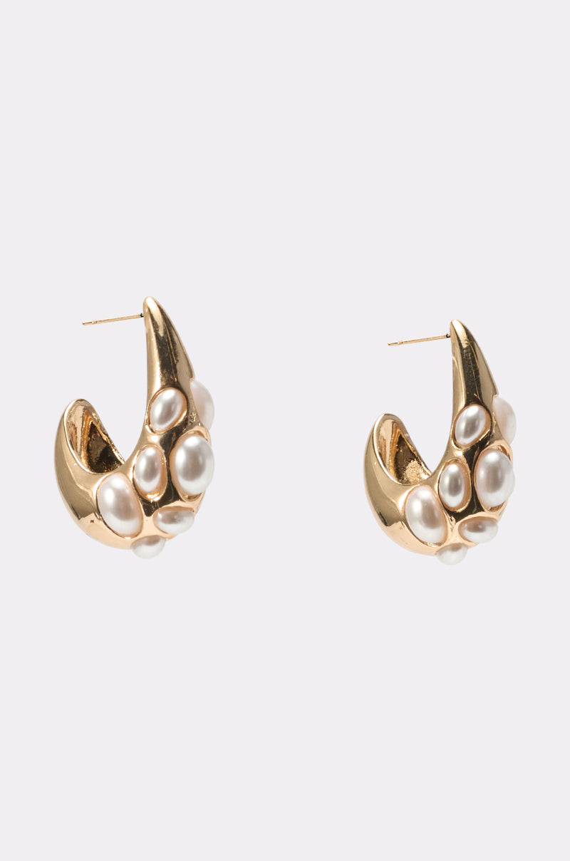 The TO THE WATER EARRING is a pair of chunky gold statement earrings decorated with multiple white pearls on the front, shown against a plain light gray background. 2