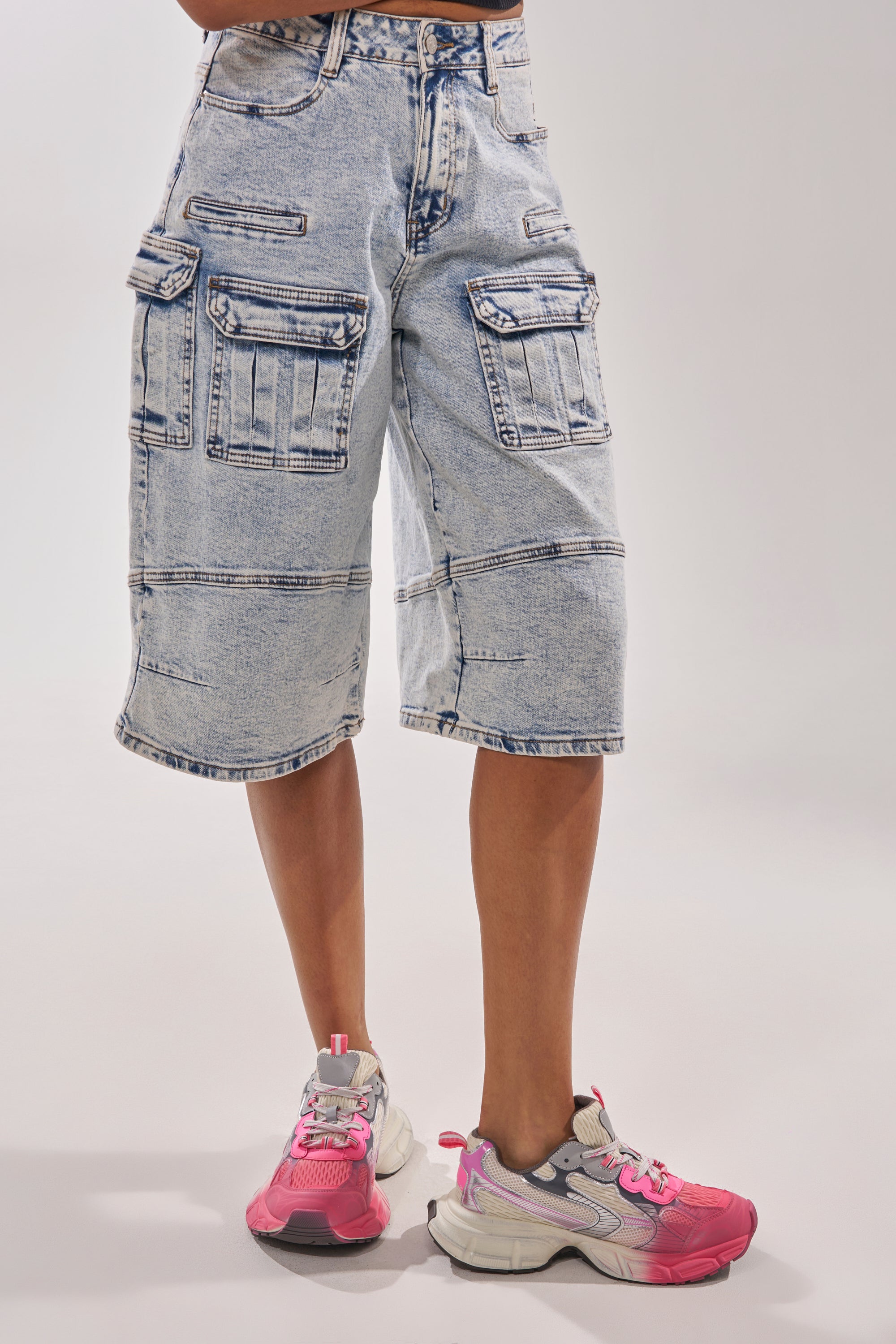 Against a plain light background, a person sports light-wash, knee-length cargo denim shorts with multiple pockets and buttons, paired with the AZALEA WANG PSI PINK LACE SNEAKER—chunky platform shoes—for a cool athleisure vibe. 0