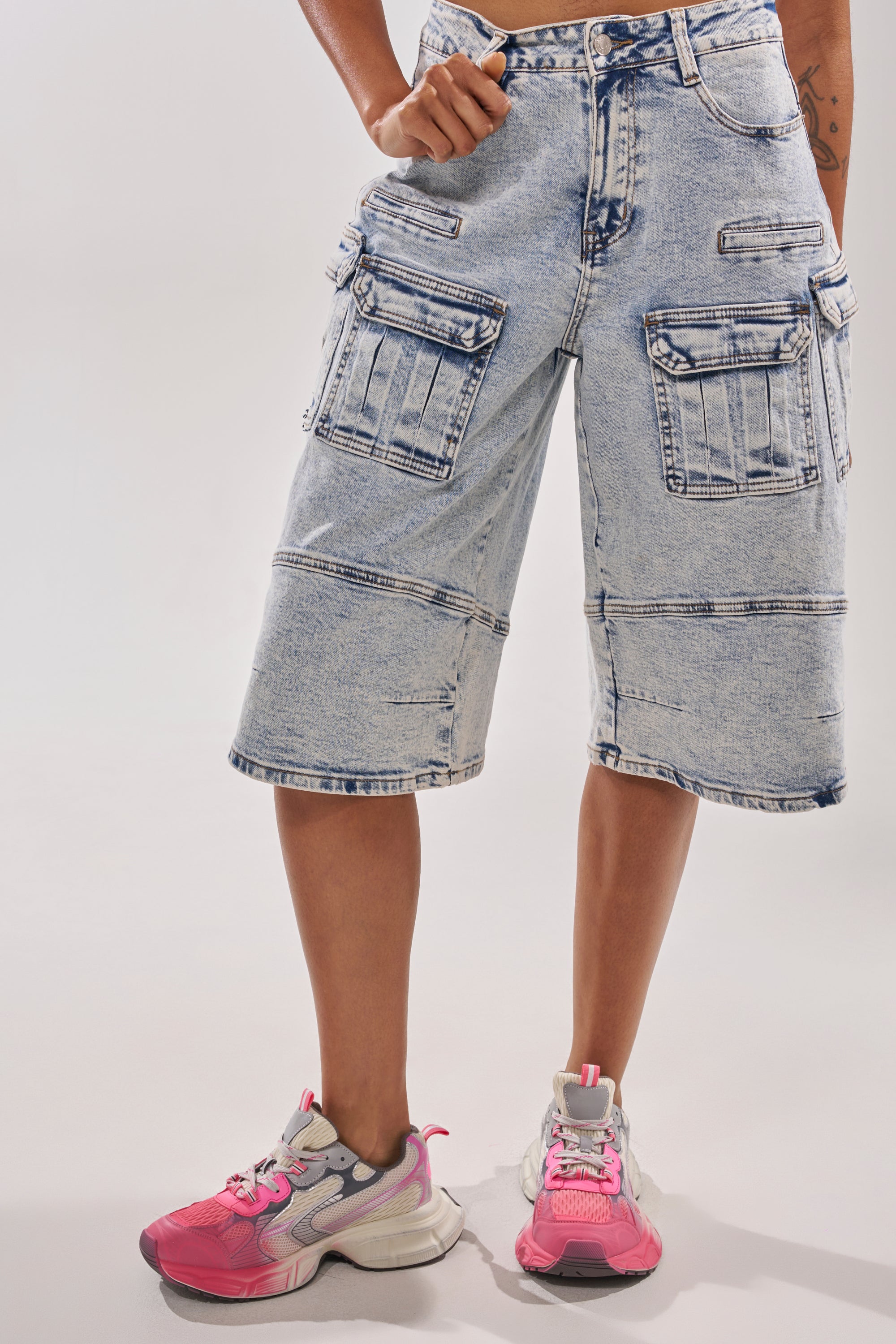 A person in light-wash, knee-length cargo denim shorts with large pockets wears AZALEA WANG PSI PINK LACE SNEAKER with a platform sole, standing against a plain white background for an easy athleisure vibe. 1
