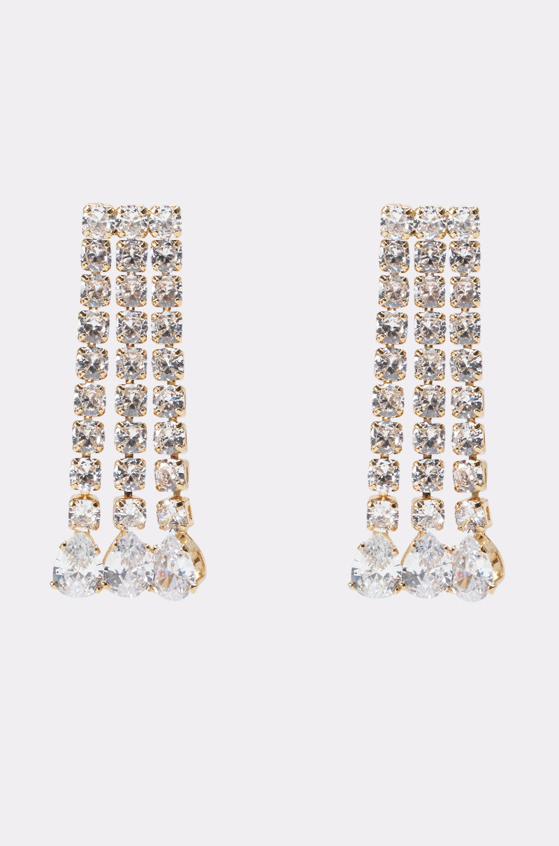 THE GO TO DANGLE EARRING features gold-tone drops with three rows of clear crystals ending in teardrop stones. These rhinestone fringe earrings are set against a plain white background. 0