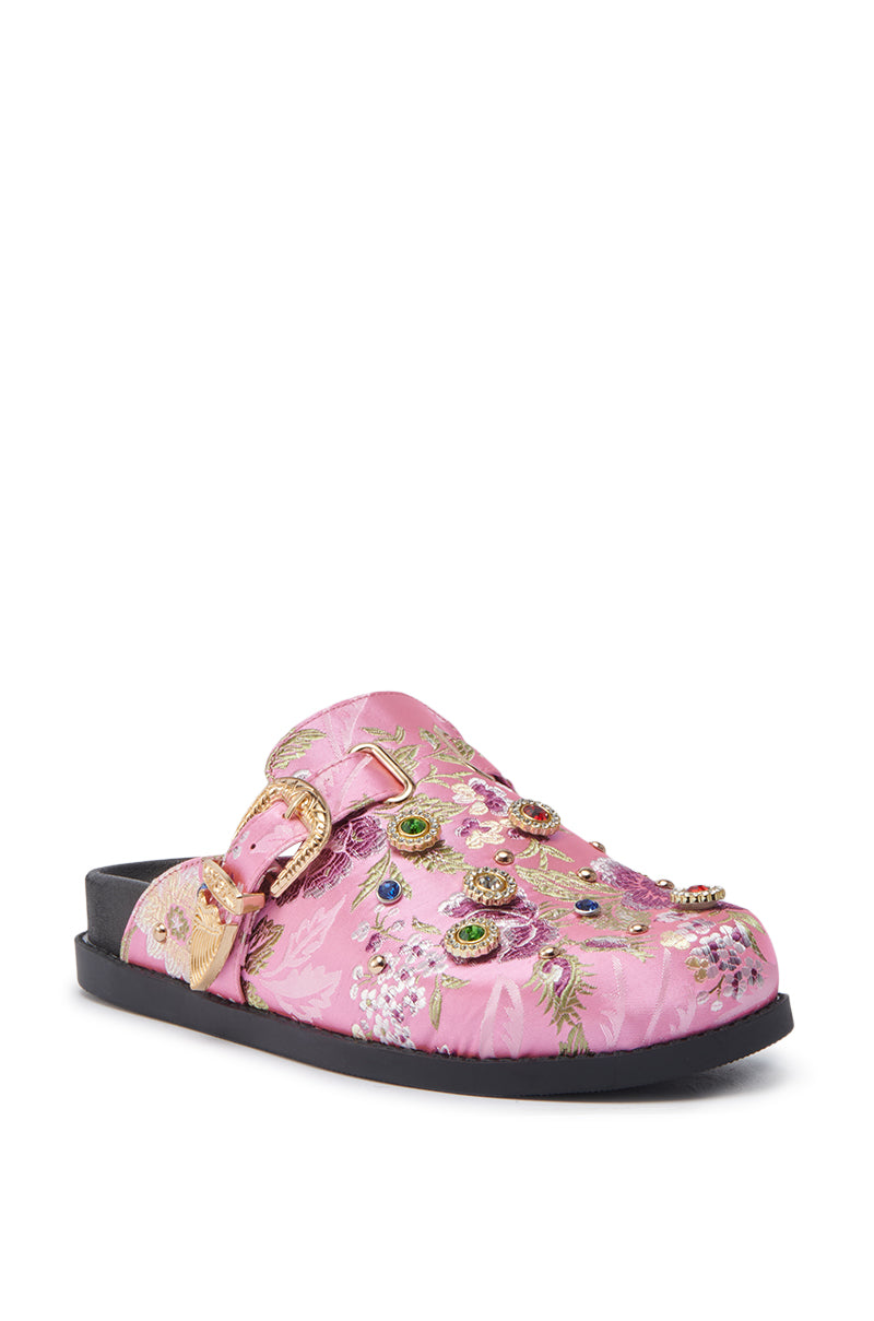 The AZALEA WANG QUINBY BROCADE CLOG IN PINK is a pink slip-on clog with a black sole, detailed floral brocade embroidery, gemstone accents, and gold buckles.