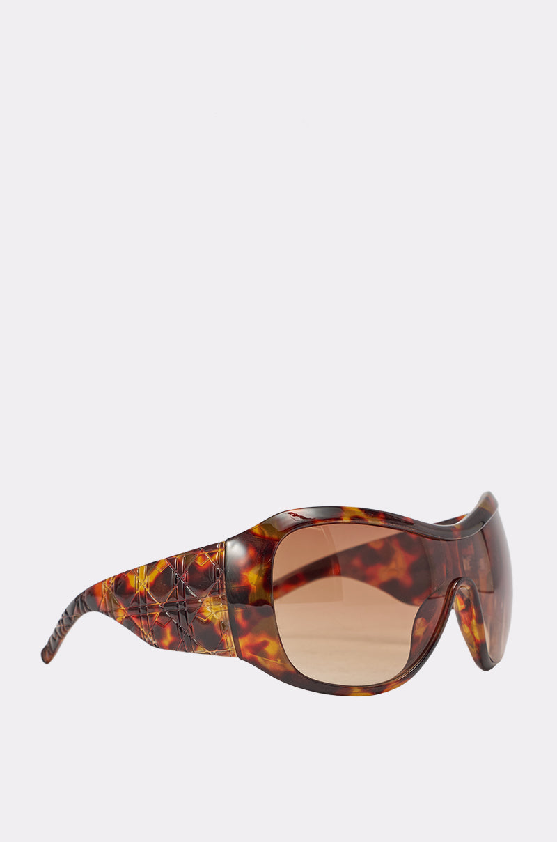 TORTALLY SUNGLASSES feature a tortoise shell wrap frame, brown gradient lenses, and thick curved arms, shown against a plain light background. 3