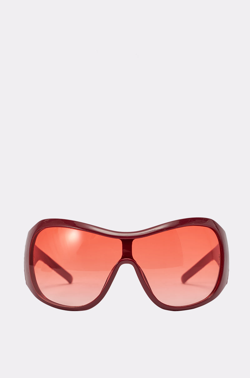 WITH LUV SUNGLASSES feature an oversized maroon frame with rounded edges and large tinted lenses. These stylish shield sunglasses are showcased against a plain light gray background. 1