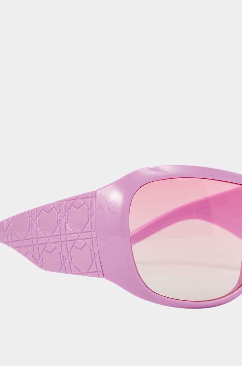 The BUBBLEGUM SUNGLASSES feature a bubblegum pink shield design with wide, diamond-patterned arms and oversized pink-tinted lenses, standing out boldly against a plain white background. 4