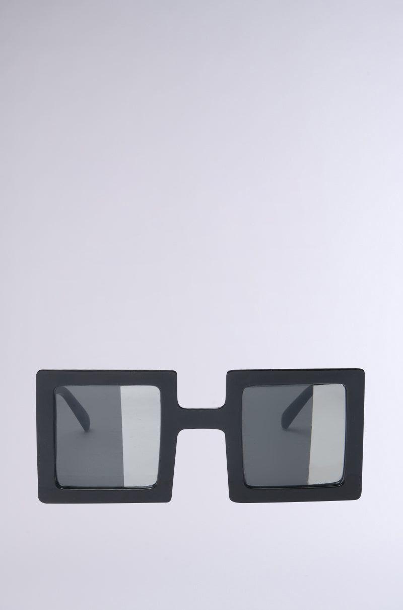The REALLY LIKE THAT SUNGLASSES feature a bold, geometric design with square, black frames and dark lenses. They are showcased on a light gray background and boast thick frames with a modern, half-mirrored style for added flair.