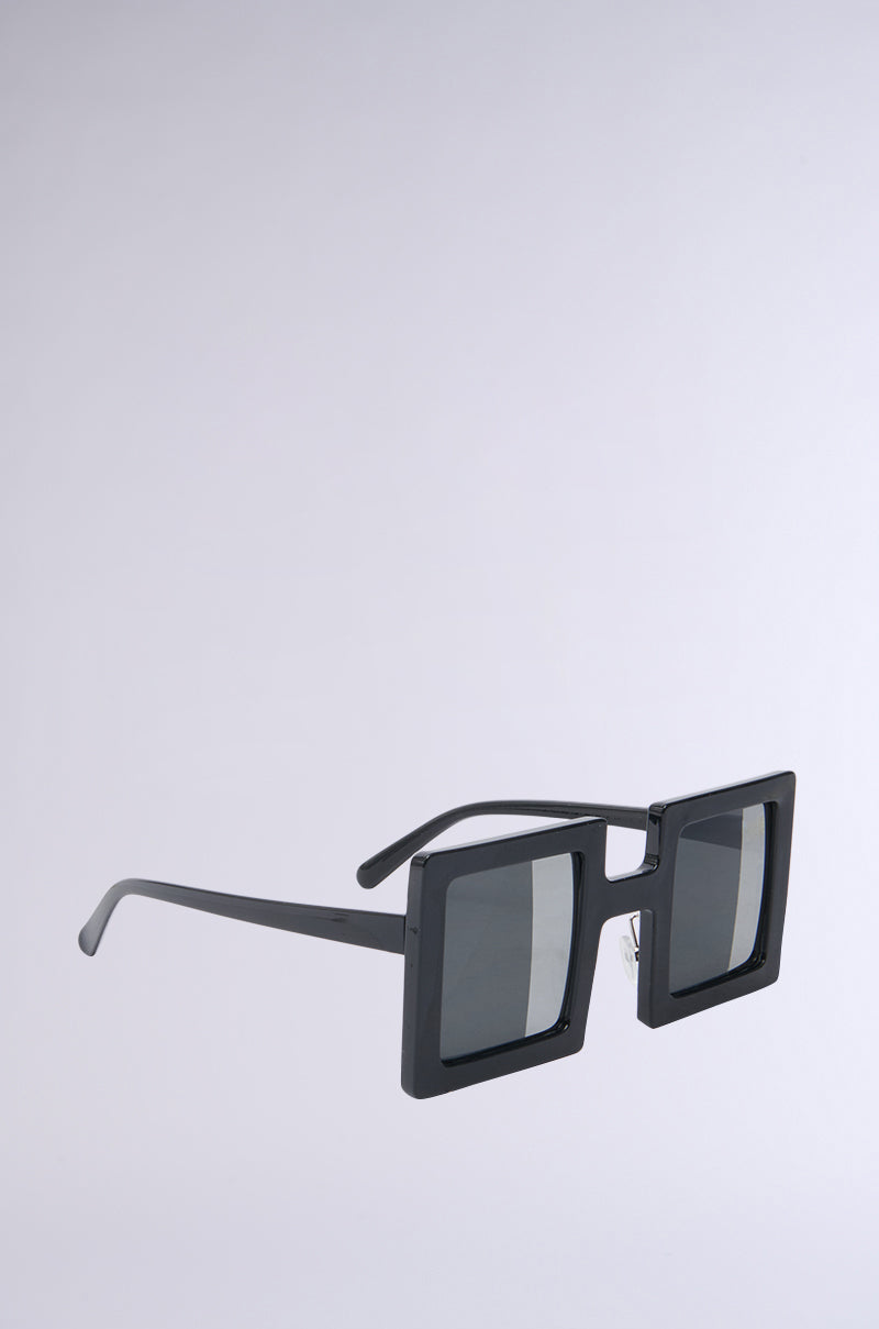 The REALLY LIKE THAT SUNGLASSES feature a sleek, modern geometric frame with angular black half-mirrored lenses. The bold style is enhanced by clean lines and a sophisticated gray backdrop.