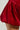 Close-up of a person wearing the chic THIS MOMENT VELVET ROMPER IN RED, showcasing a softly gathered, flared bubble silhouette. The fabric shines slightly, highlighting its rich texture. A neutral background draws focus to this stylish piece.