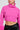 A person is wearing the SYDNEY FUR CUFF CROPPED SWEATER IN HOT PINK, perfectly paired with a pleated black leather skirt, and complemented by large hoop earrings.