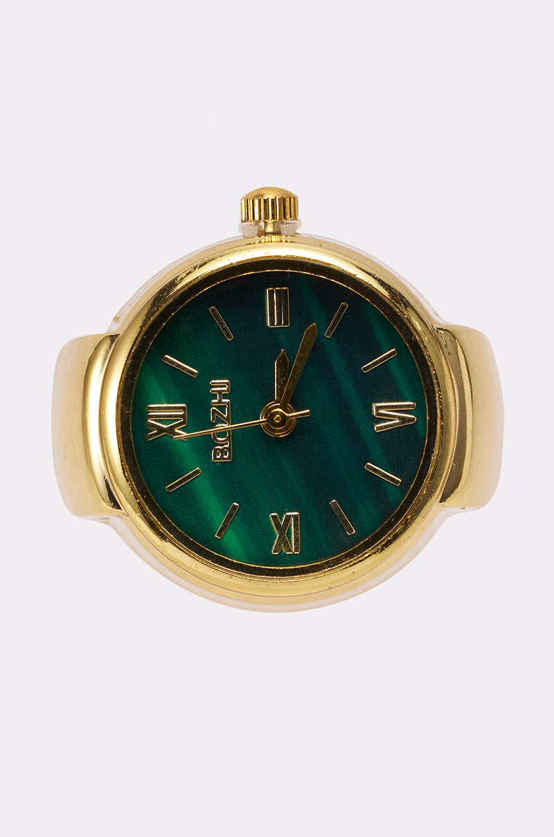 The WHAT TIME IS IT RING features a gold band with a green marbled face, gold Roman numerals, and gold hands, all set against a plain light background.