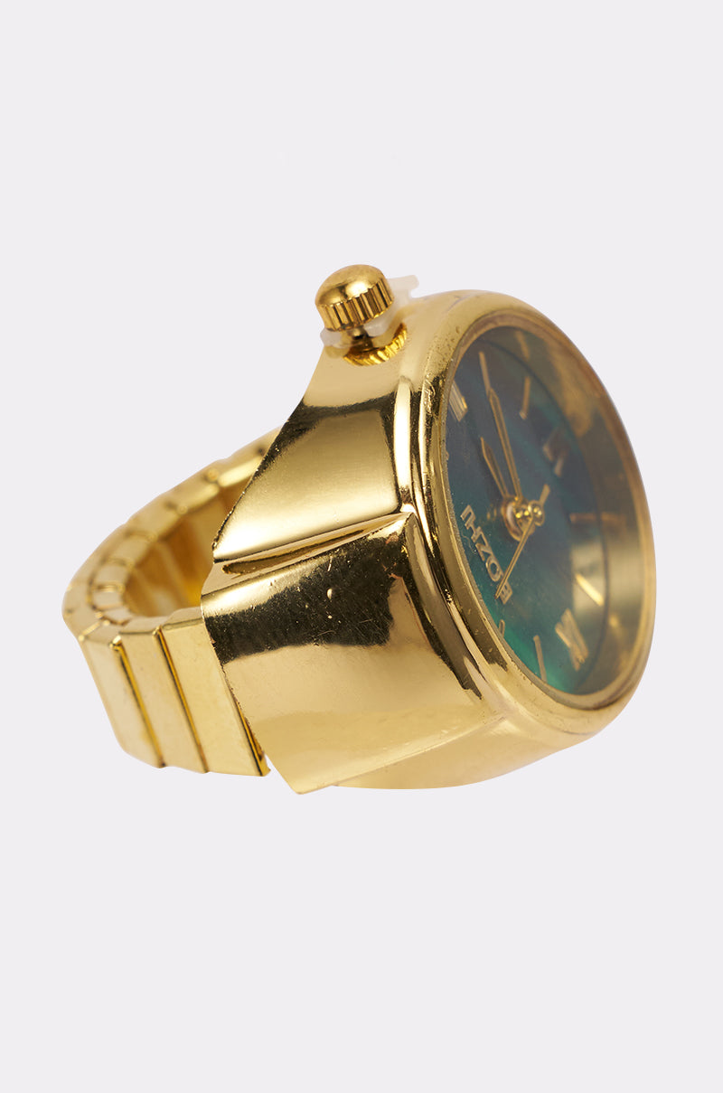 The WHAT TIME IS IT RING is a gold wristwatch with a metallic band and round face, featuring a greenish-black dial and highlighted gold ring, showcased from the side and front against a plain light background.