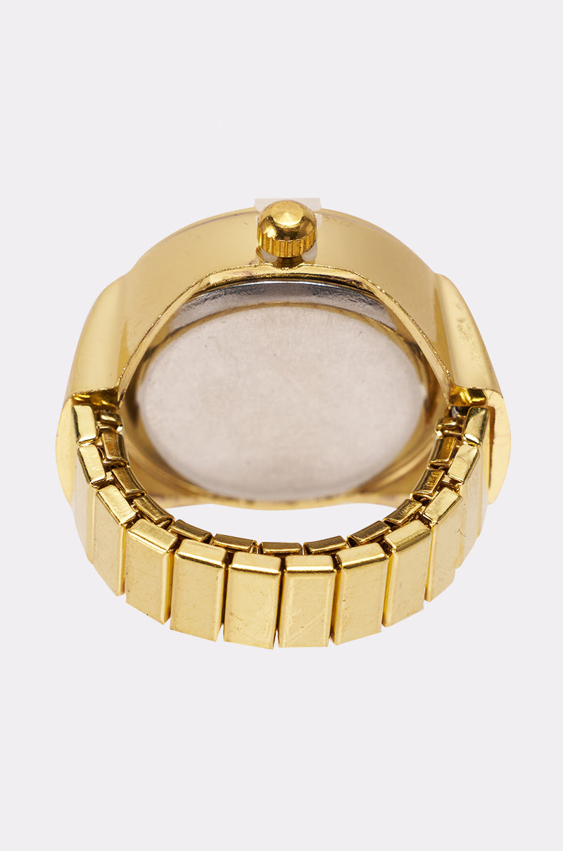 A close-up of the WHAT TIME IS IT RING shows its elegant gold metallic band and case, focusing on the blank watch back and winding crown for a stylish detail view.