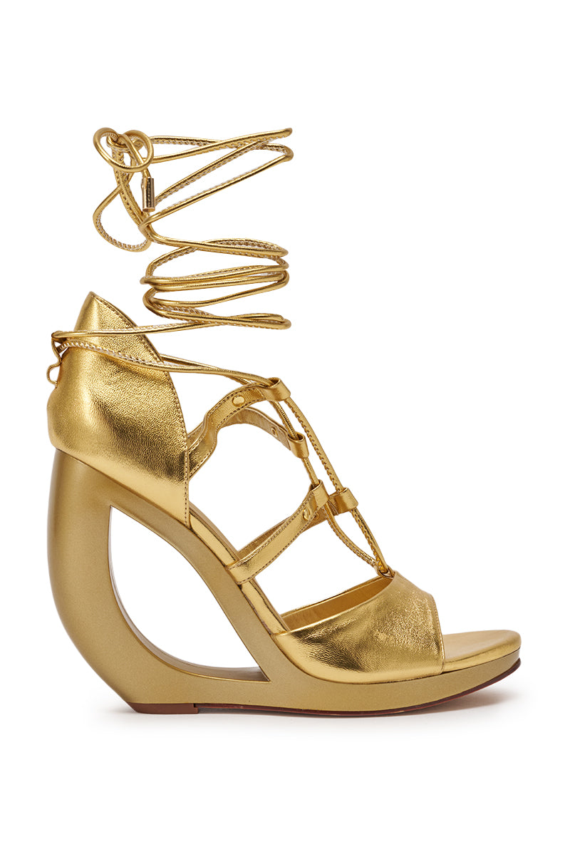 The AKIRA GOLD RACHNA GOLD WEDGE OPEN TOE SANDAL features a metallic gold finish, sculpted wedge heel, multiple thin straps, long lace-up ties, faux leather construction, and a comfort cushion insole for stylish support. 4
