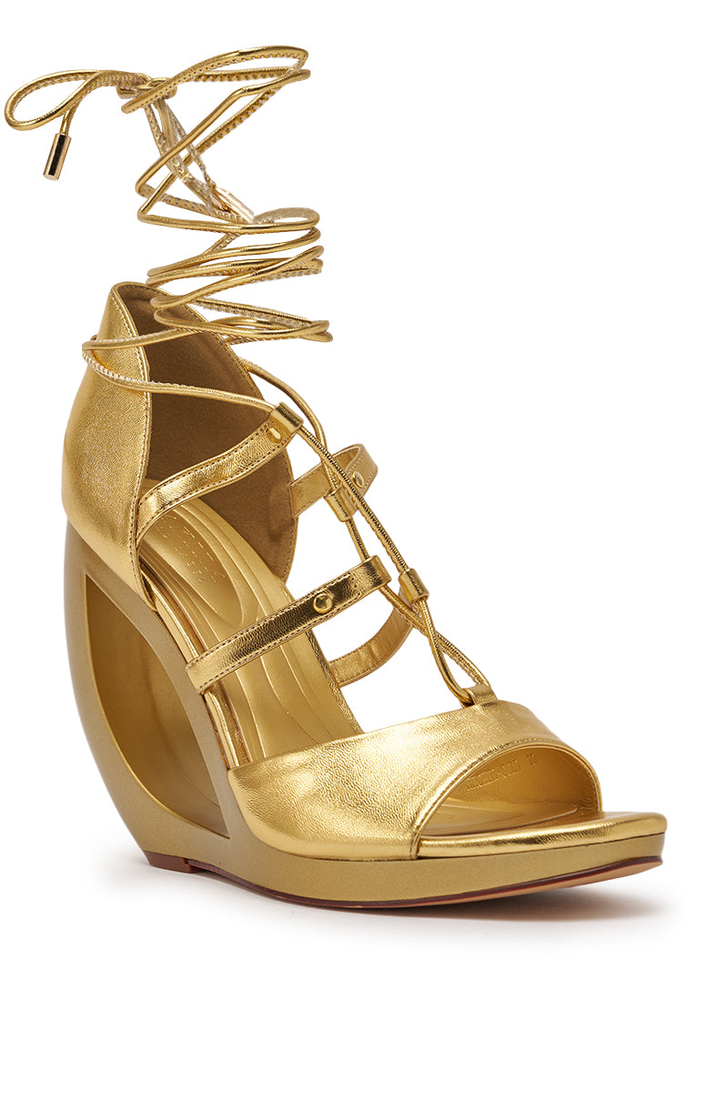 The AKIRA GOLD RACHNA GOLD WEDGE OPEN TOE SANDAL features a unique curved metallic wedge, open toe, and multiple thin straps with long laces for ankle wrapping—ideal standout gold wedge sandals for any occasion. 5
