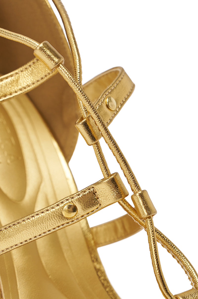 Close-up of the AKIRA GOLD RACHNA Gold Wedge Open Toe Sandal, featuring metallic gold premium faux leather, small gold rivets, and a comfort cushion insole, set against a white background. 7