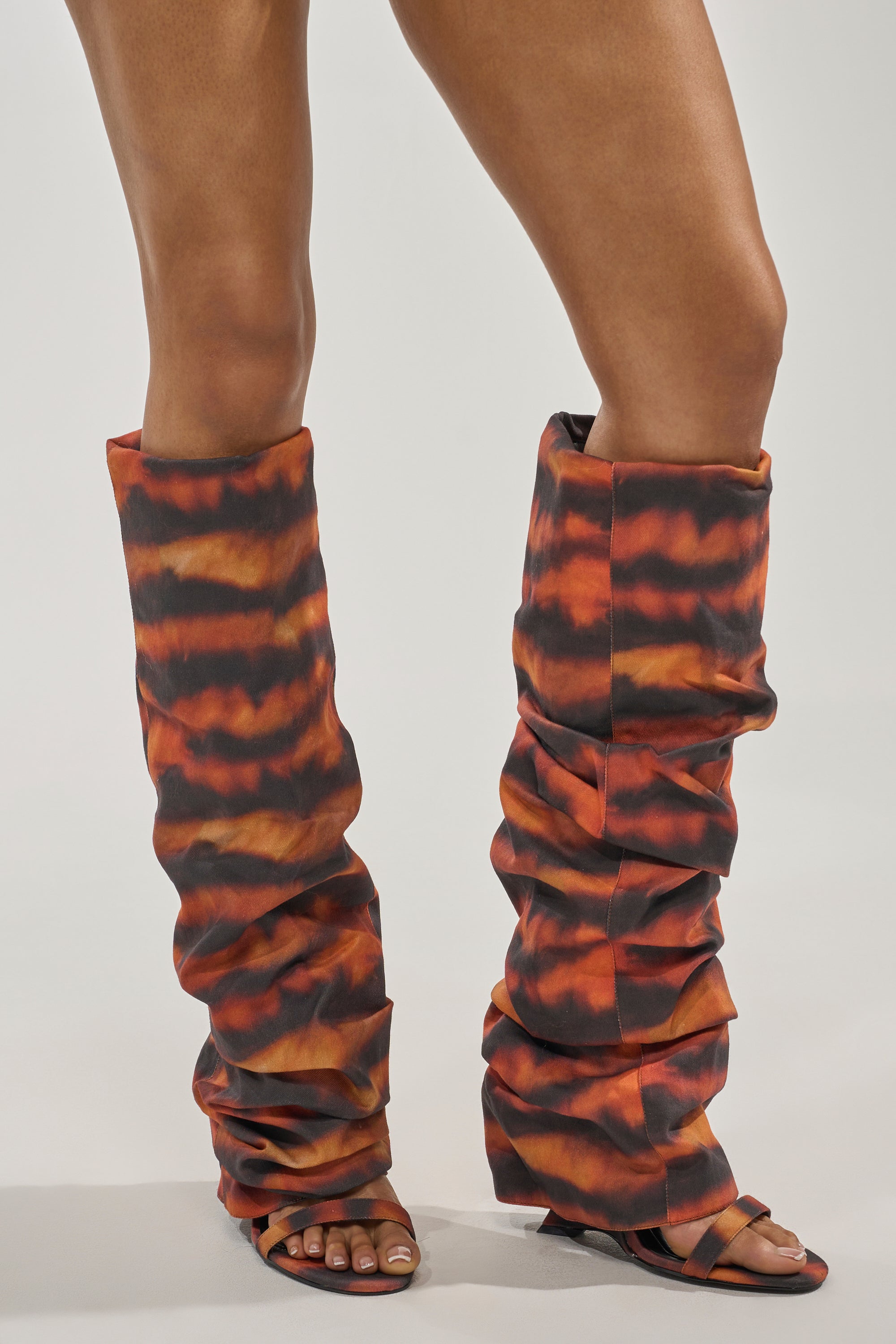 Wearing the AZALEA WANG RADLEY TIGER PRINT SLOUCHY WEDGE BOOT paired with open-toe heeled sandals, someone channels Y2K style in orange, black, and brown tiger print against a light background. 1