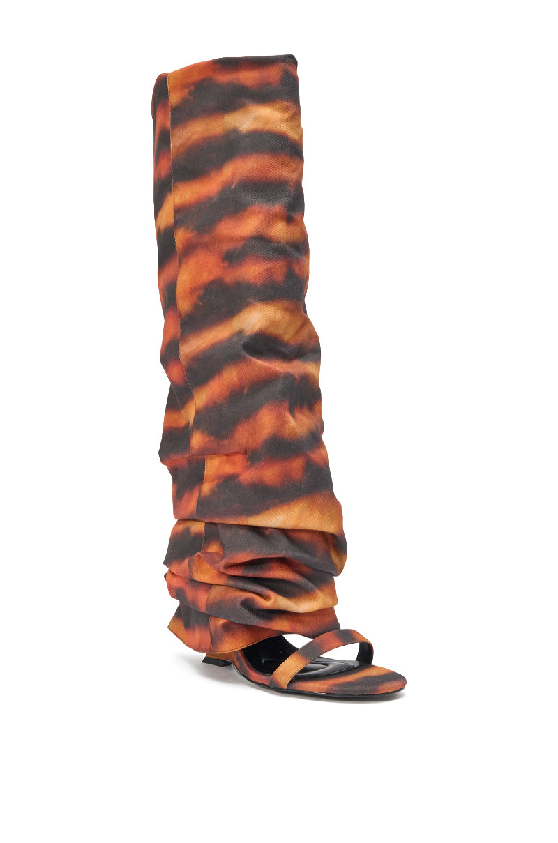The AZALEA WANG RADLEY TIGER PRINT SLOUCHY WEDGE BOOT features Y2K style with a bold orange, brown, and black tiger-stripe print, open toe, low wedge heel, and knee-high loose ruched fabric for a standout look. 3