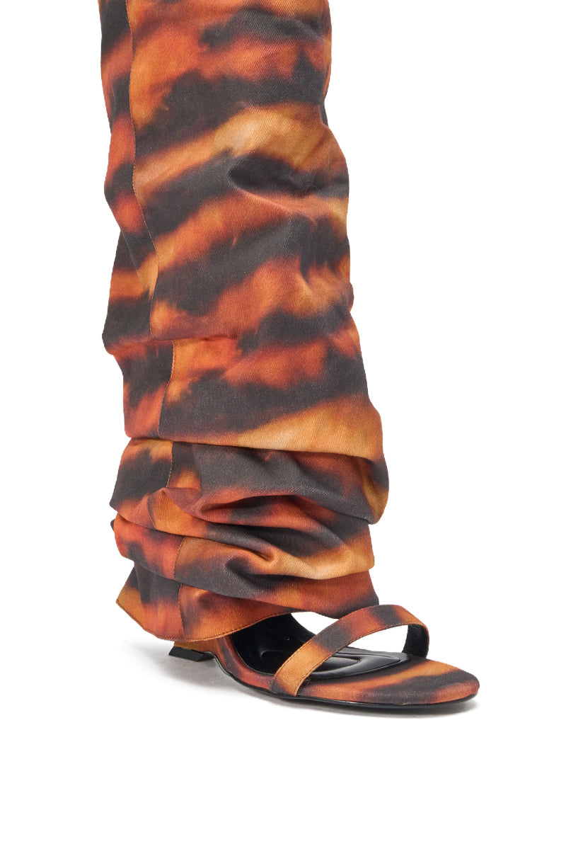 A close-up of a person wearing the AZALEA WANG RADLEY TIGER PRINT SLOUCHY WEDGE BOOT in a bold orange and black tiger pattern, showing only the foot and lower leg. 5