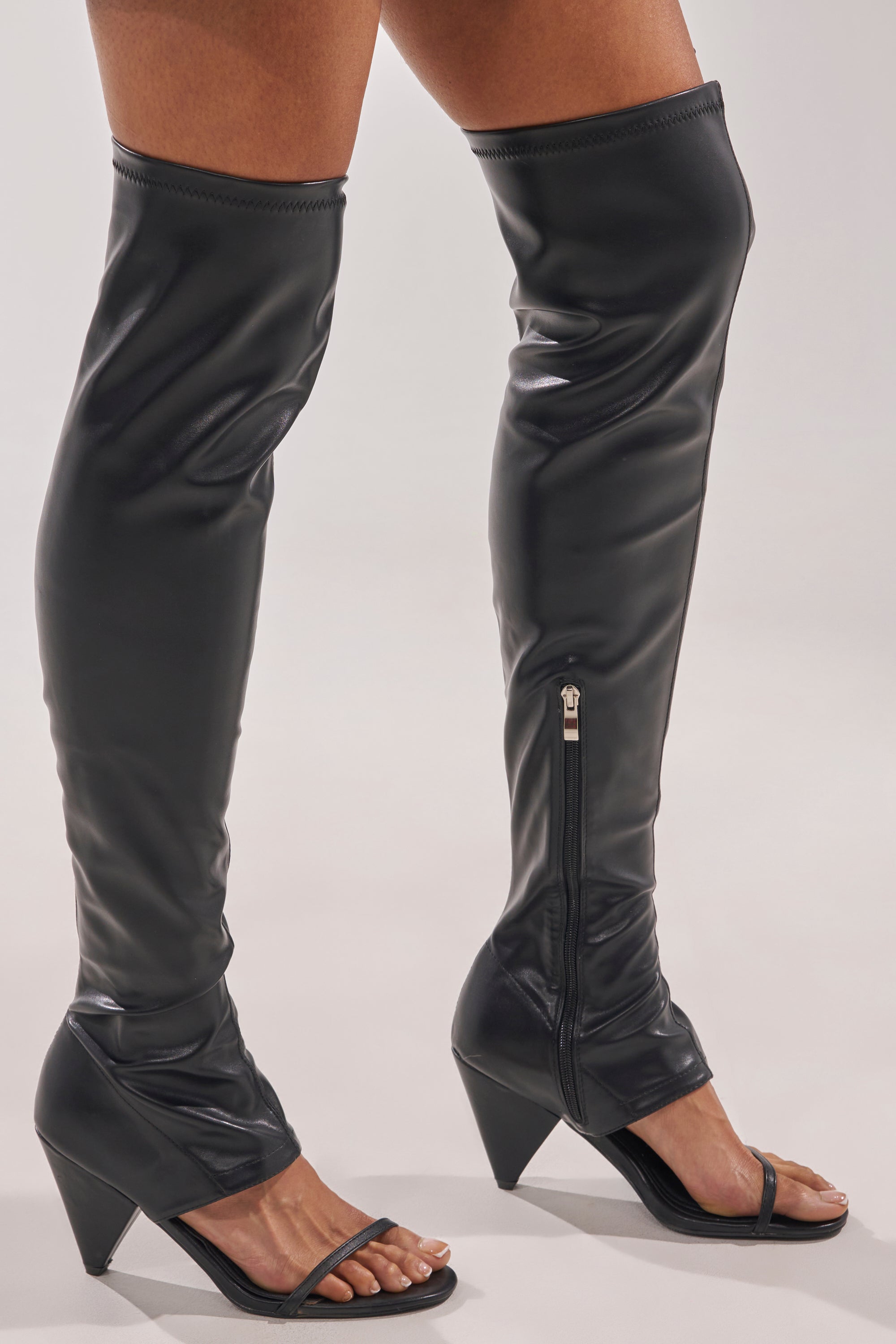 Someone wearing AZALEA WANG RAGNAR Black Chunky Stretch PU Over The Knee Boots stands on a light surface. 1