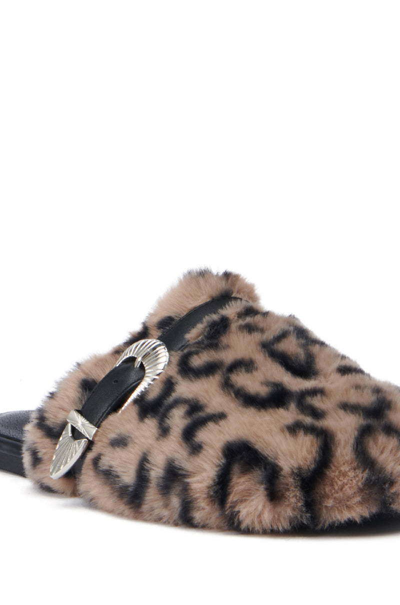 A close-up of the AZALEA WANG RAMIE LEOPARD MULE FLAT highlights its fuzzy animal print design, complemented by a silver buckle accent on a black strap. This slipper features a cushioned insole and faux fur upper, set against a plain white background.