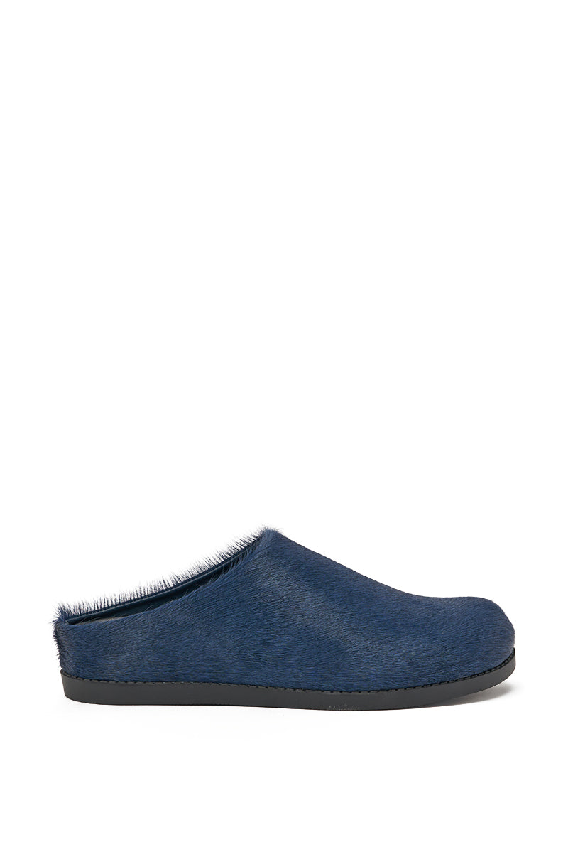 The AZALEA WANG RAMSES NAVY SLIP ON FLAT features a navy mule design with a textured genuine calf hair upper, flat black sole, and slip-on style, shown in profile against a white background. 3